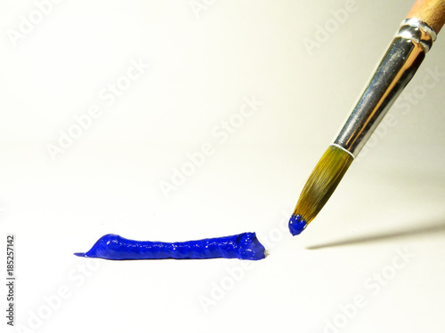 Blue acrylic paint on the brush and on a sheet of paper.