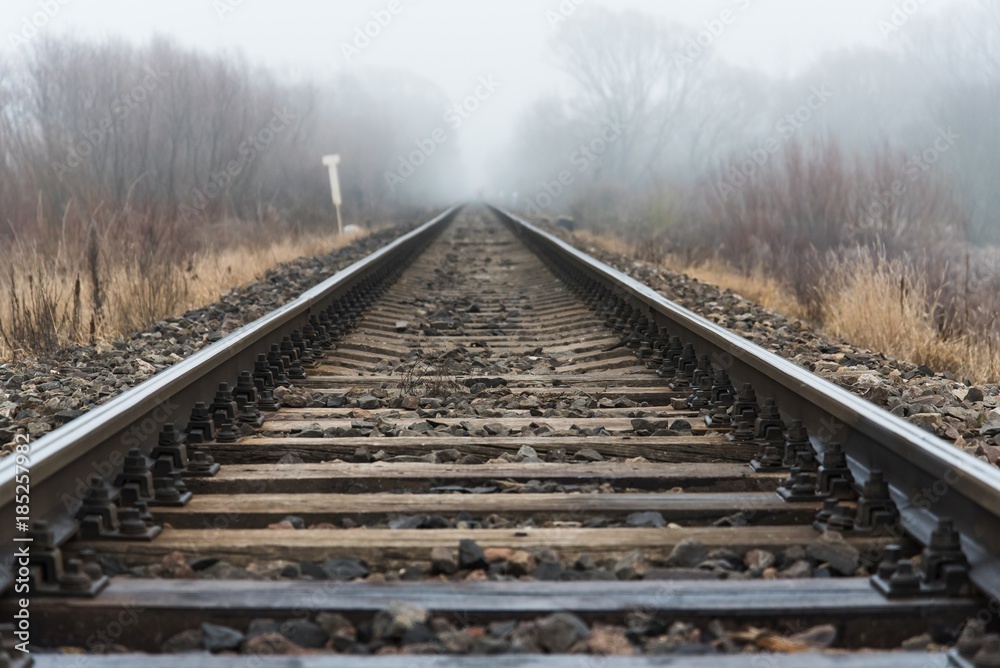 Empty railroad track going into a fog, outdoor landscape