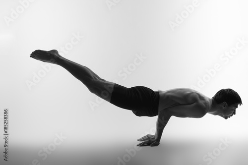 Young attractive man shows poses in yoga