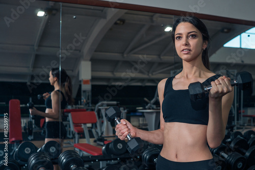 Sports girl exercising with dumbbells in the gym