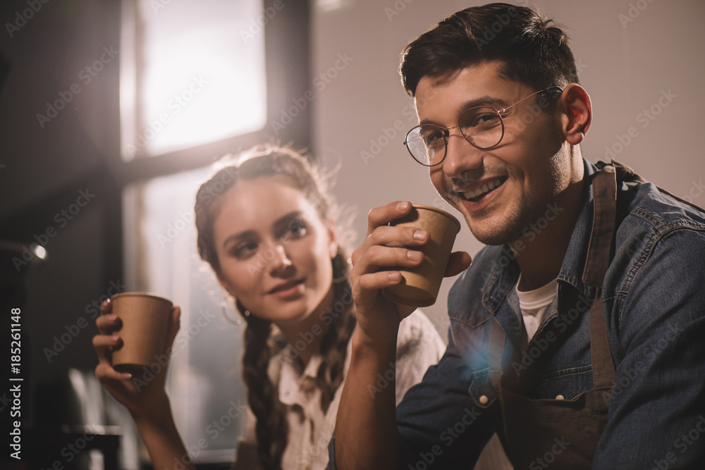 couple with cups of coffee having break during work at coffee shop