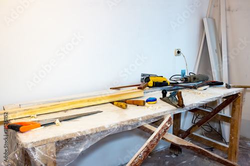The table with the tools of a carpenter. On the table saw, planer, chisels, tape measure, electric jigsaw and a drill