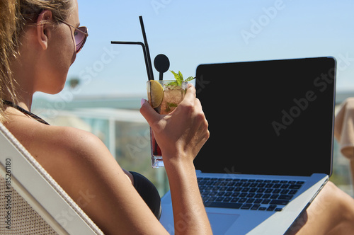 Kobieta pracująca na laptopie. Dziewczyna na wakacjach. Praca w podróży. Praca zdalna. Na basenie.