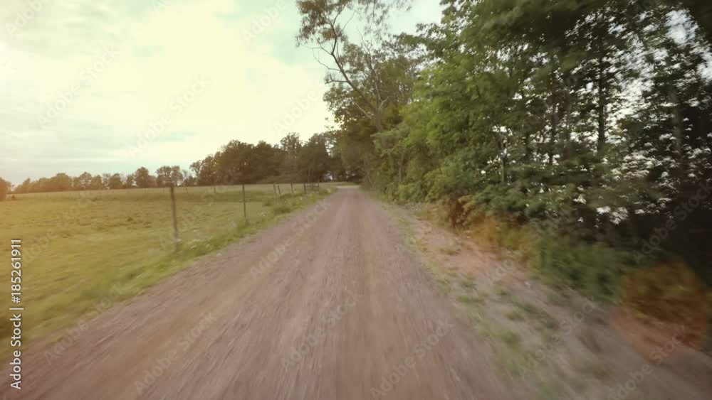 Riding bike on rural road in sunshine. Summer leisure activity in pov perspective. 