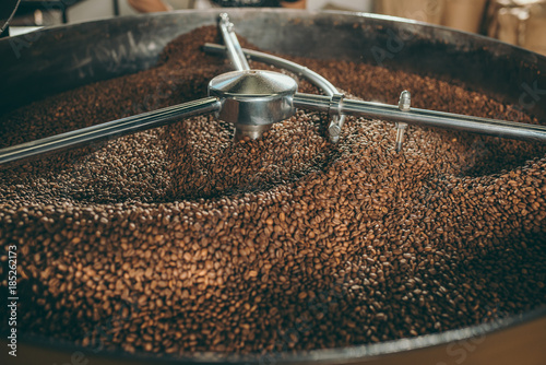Fototapeta close up view of coffee beans roasting in machine