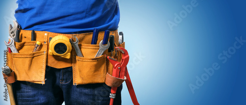 closeup of handyman tool belt on blue background with copy space