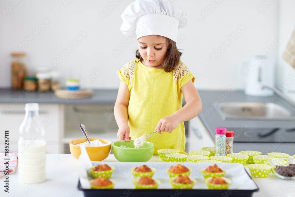 little girl in chefs toque baking muffins at home little girl in chefs toque baking muffins at home