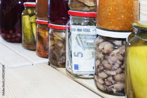 five euros in a glass jar on the background of canned food photo