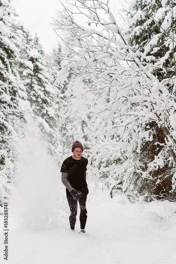 Young man running in the snow in a forrest in Austria