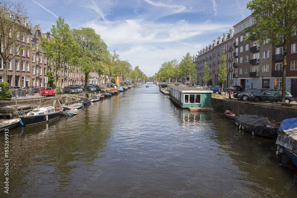 Amsterdam, the Netherlands - 23 May 2017: perspective view on canal Lennepkade boarded with boats and house boats and brick buildings