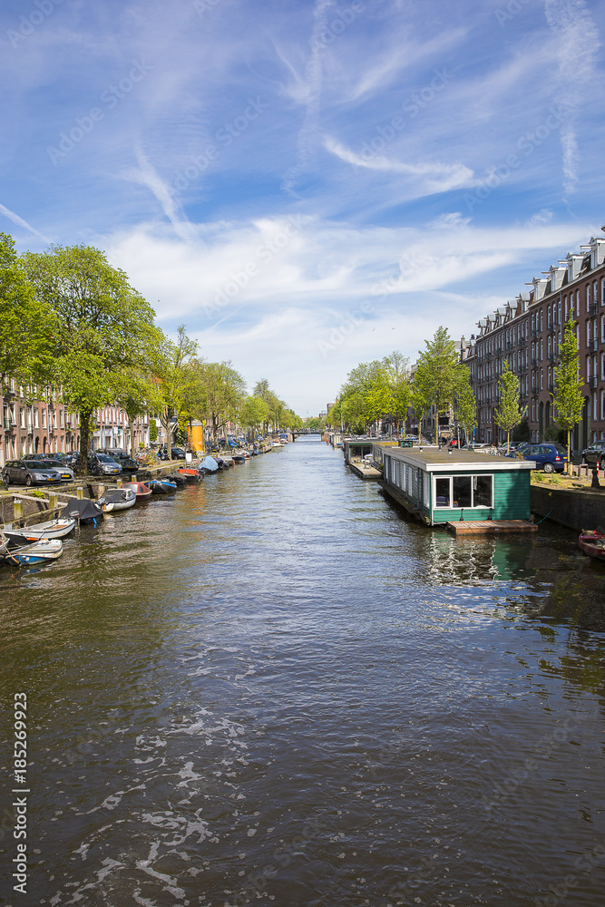 Amsterdam, the Netherlands - 23 May 2017: perspective view on canal Lennepkade boarded with boats and house boats and brick buildings