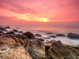 Fotobehang Koraal Zachte zonsopkomst aan rotsachtig strand  © abnohr