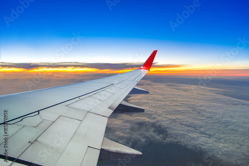 Plane wing on the sky with sunset and cloud, aerial view from airplane window.