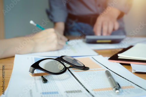 Business concept with copy space. Office desk table with business executives discussing or analysis chart report paper and calculator on desk.Vintage effect.Selective focus at glasses.