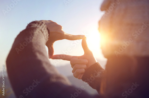 Close up of woman hands making frame gesture with sunrise on moutain, Female capturing the sunrise, Future planning, sunlight outdoor. photo