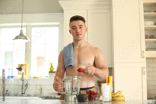 Young man with no shirt on making a healthy smoothie. 