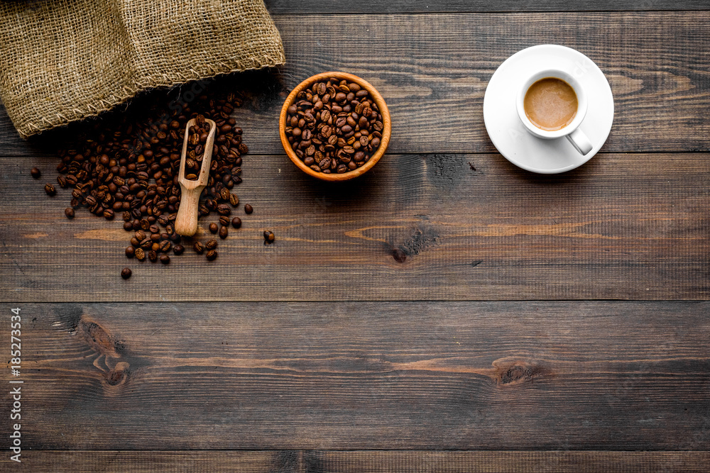 Fototapeta premium Fresh roasted coffee beans in bowl and scoop near canvas on dark wooden background top view copyspace