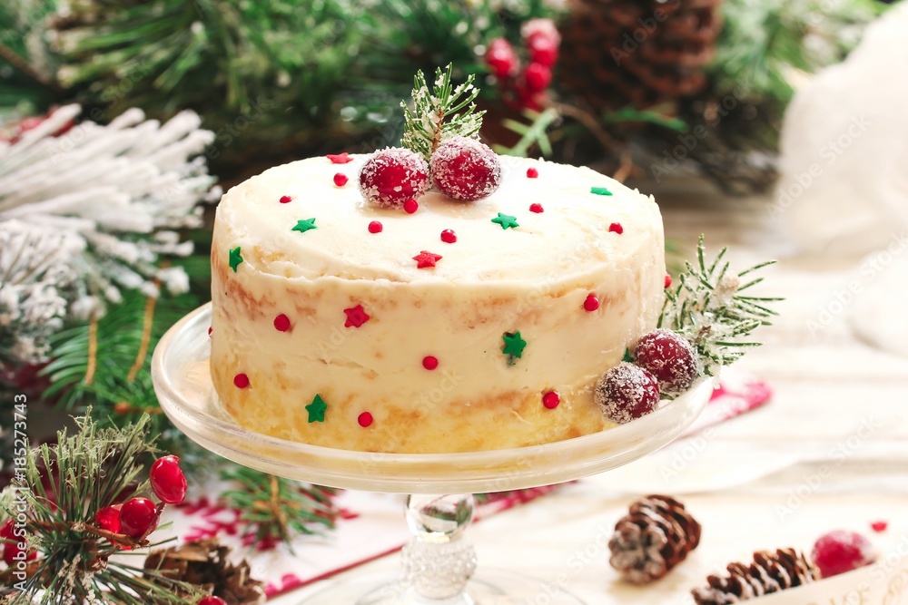 Homemade Xmas cake with white frosting sugar cranberries fir branches on Christmas frame, selective focus Homemade Xmas cake with white frosting sugar cranberries fir branches on Christmas frame, selective focus