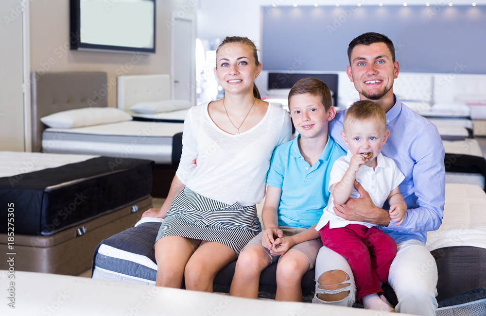 Obraz premium Young cheerful family sitting on bed in store