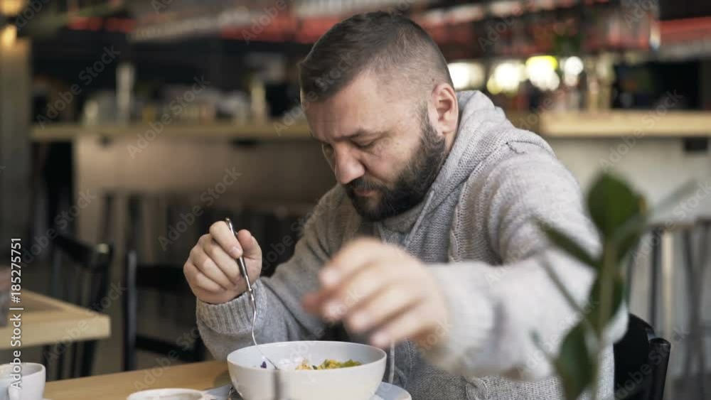Young man eating meal sitting in restaurant
