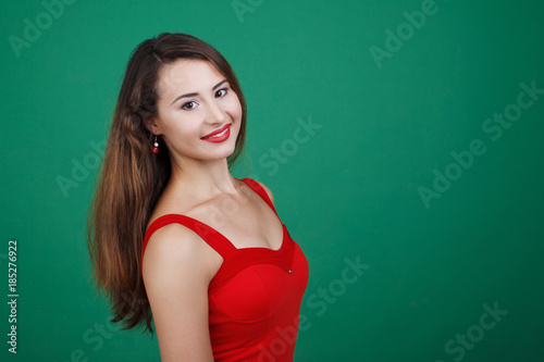 Young beautiful girl in red dress isolated green background. © olgasparrow