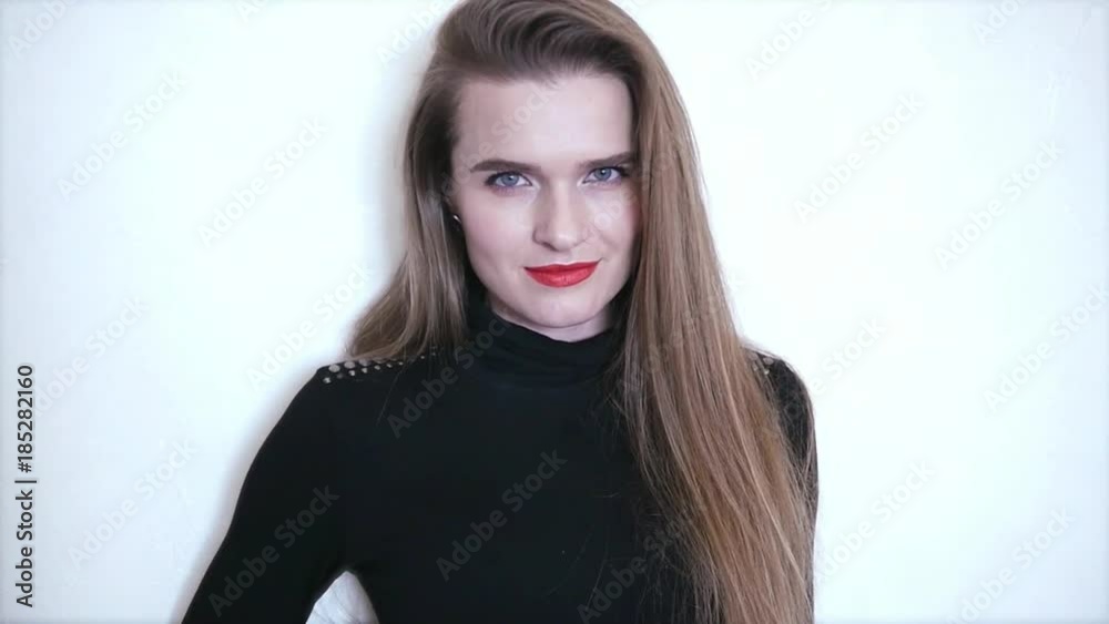 Attractive young girl with long hair and red lipstick is standing on white background and posing on camera. HD, 1920x1080, slow motion Attractive young girl with long hair and red lipstick is standing on white background and posing on camera. HD, 1920x1080, slow motion