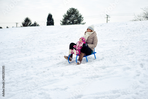 Behang Mother and daughter tobogganing on snow