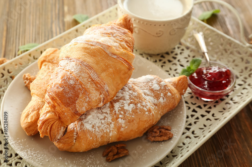 Vintage tray with tasty croissants on wooden table, closeup