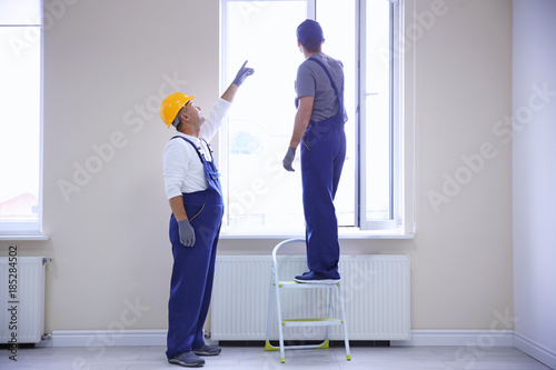 Construction worker with trainee installing window in house