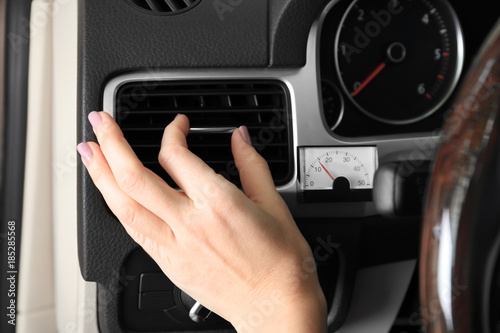 Woman adjusting air conditioner in car, closeup
