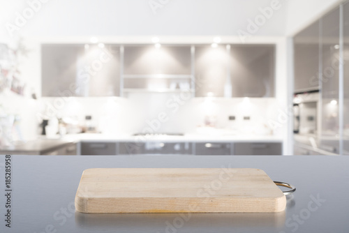 Empty cutting board on steel table with blurred modern kitchen background. Ready for product montage.