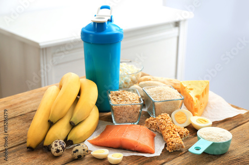 Scoop with protein powder, shake in bottle and products on table