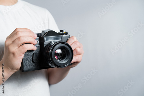 old SLR film camera in the hands of a child in a white t-shirt