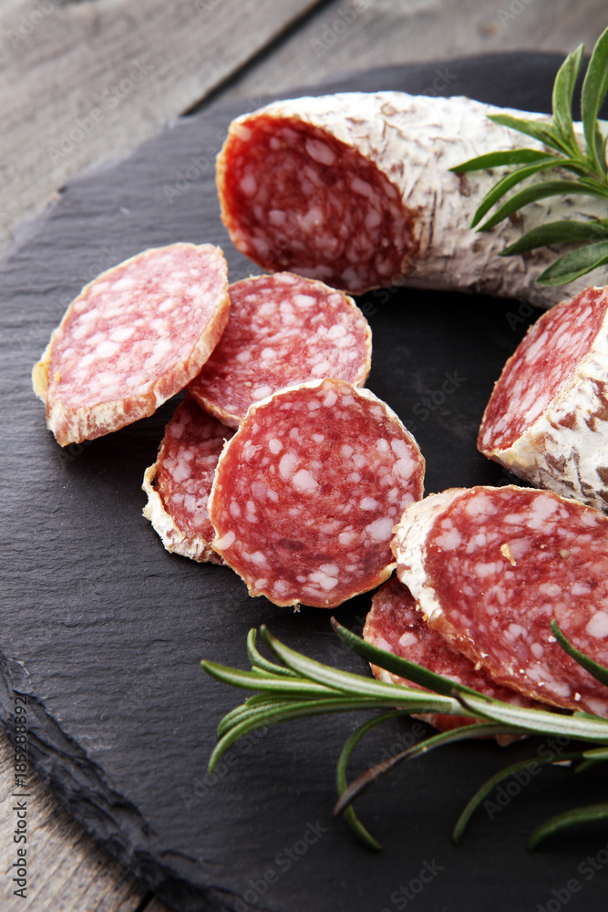 Stone cutting board with sliced salami on it Stone cutting board with sliced salami on it