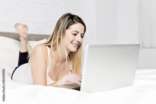 Young woman using laptop on bed