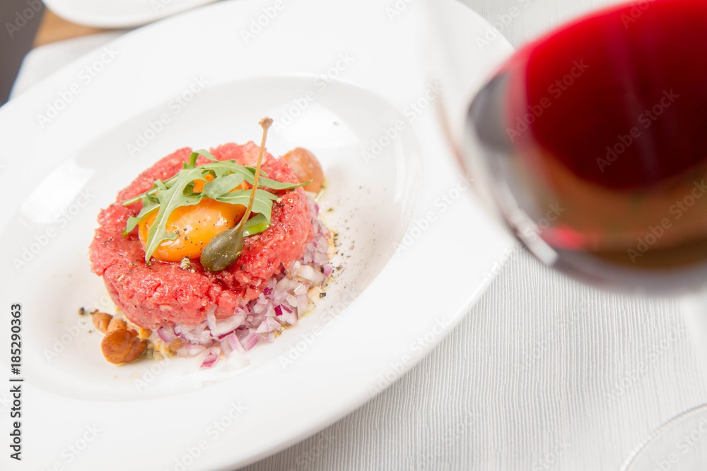 Steak tartare served in a restaurant with egg yolk, onion, pickles, caper, mushroom and rocket salad Steak tartare served in a restaurant with egg yolk, onion, pickles, caper, mushroom and rocket salad