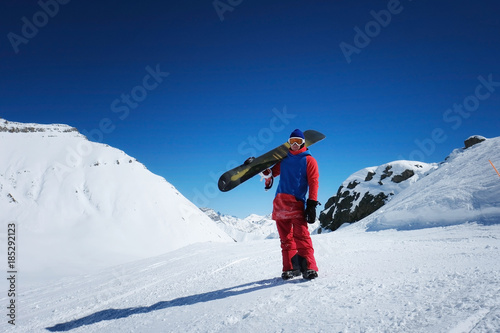 male sportsman snowboarder stands against the background of mountains