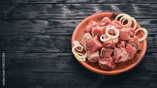 Raw uncooked meat sliced in cubes on wooden rustic background, top view.