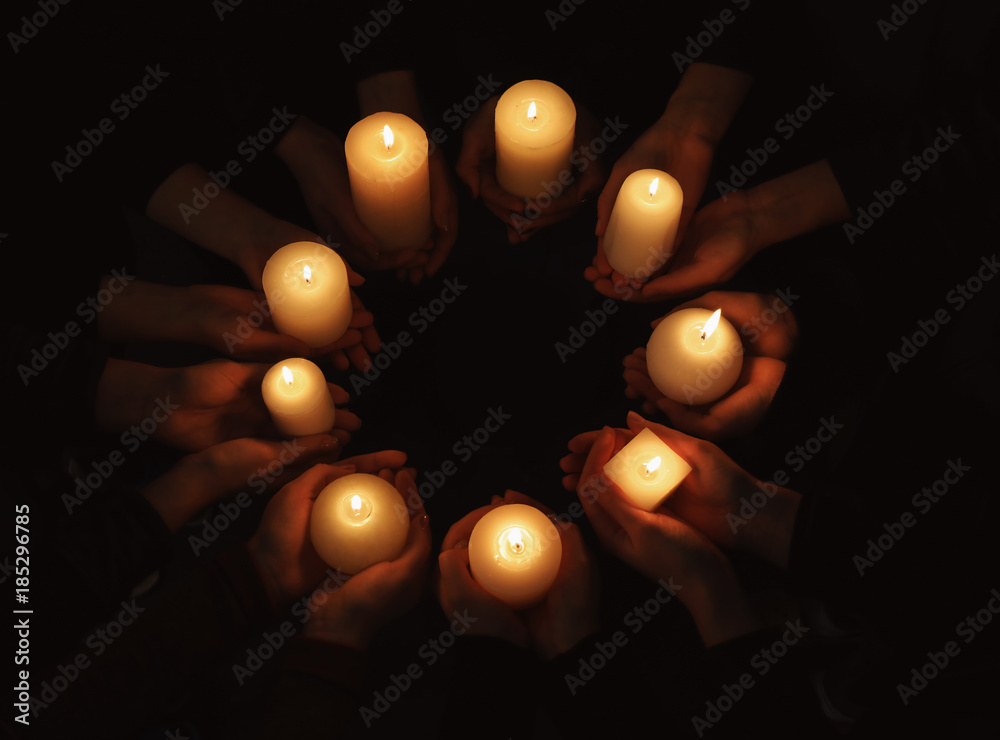Fototapeta premium Hands with burning candles on dark background