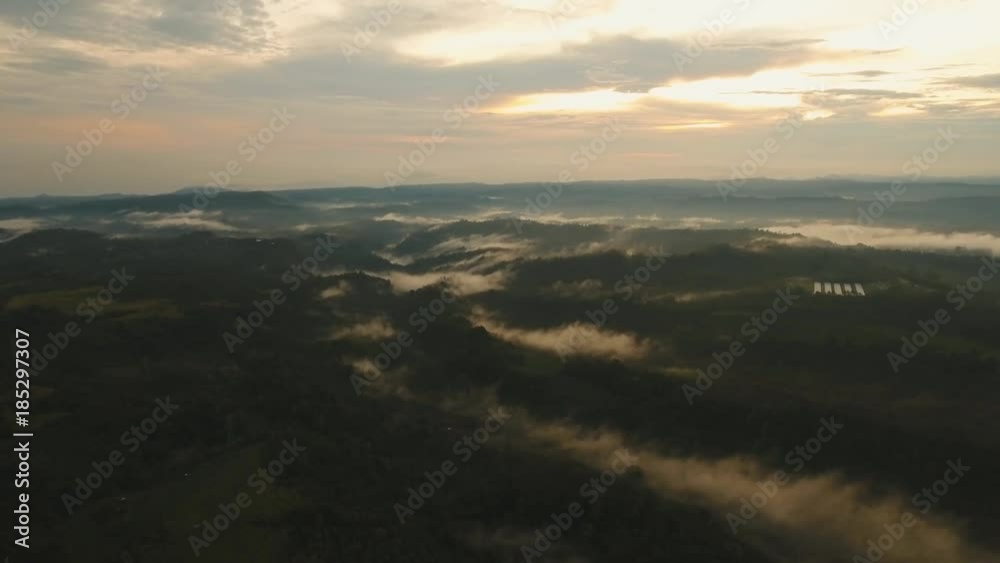 Aerial view of forest, mountains with fog, clouds at sunset on Bali,Indonesia. Tropical rainforest, trees, jungle in mountains. Fog over the jungle. Travel concept. Aerial footage. Aerial view of forest, mountains with fog, clouds at sunset on Bali,Indonesia. Tropical rainforest, trees, jungle in mountains. Fog over the jungle. Travel concept. Aerial footage.