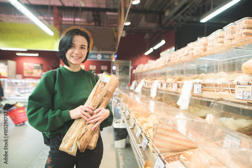 A smiling buyer at a supermarket. Positive girl with bread in the hands of a supermarket. The girl buys bread at a supermarket.