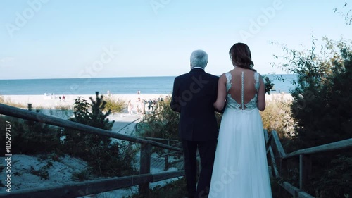 father leads a daughter/bride to the wedding altar for a wedding ceremony on the beach near the sea