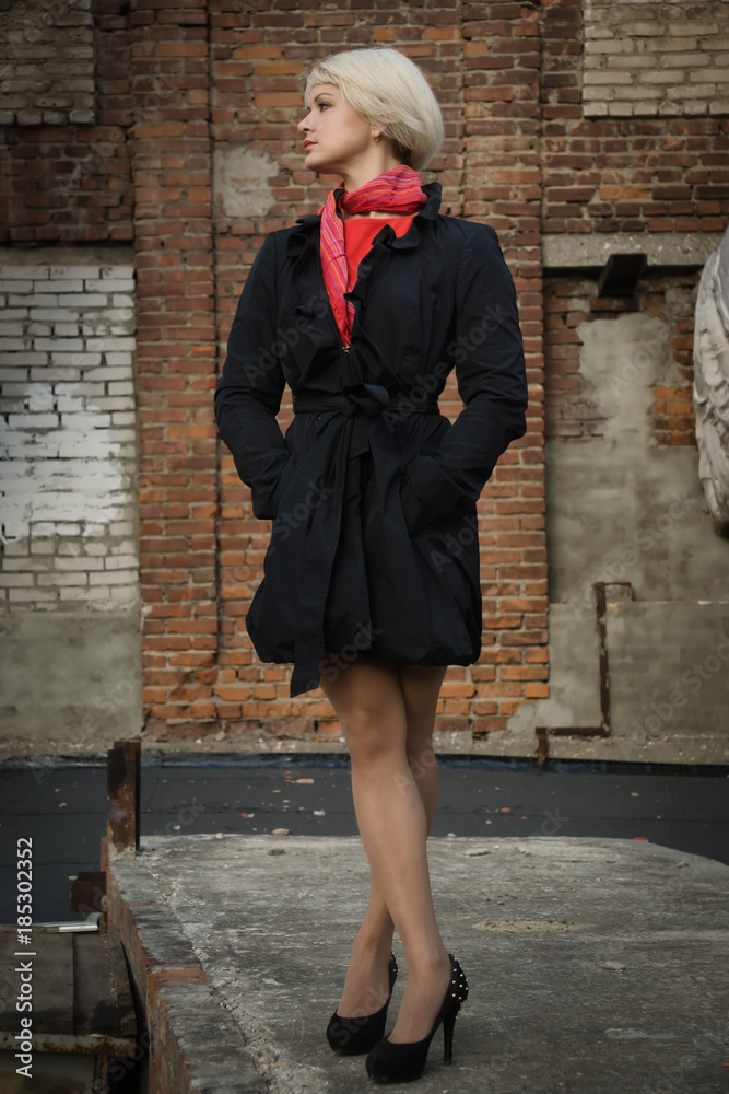 Noir film style woman in a black suit and red dress posing in a street
