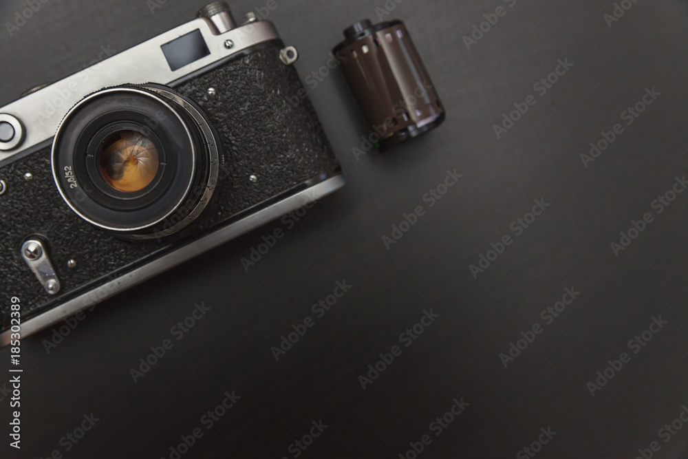 Vintage Film Camera And Roll On Black Wooden Background Technology Development Photographer Concept with copy space. Top View