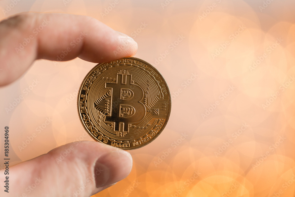 Man holding golden bitcoin. On the background blurred bokeh lights. the concept of cryptocurrency Man holding golden bitcoin. On the background blurred bokeh lights. the concept of cryptocurrency