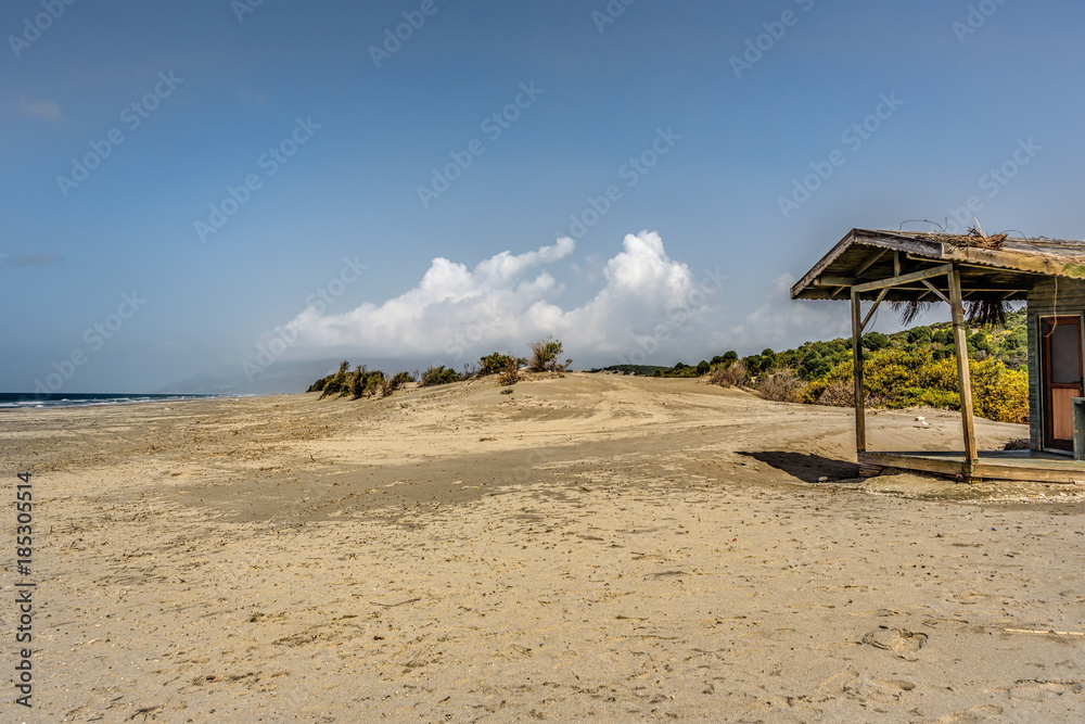 Wide sandy beach under blue skies with scattered clouds