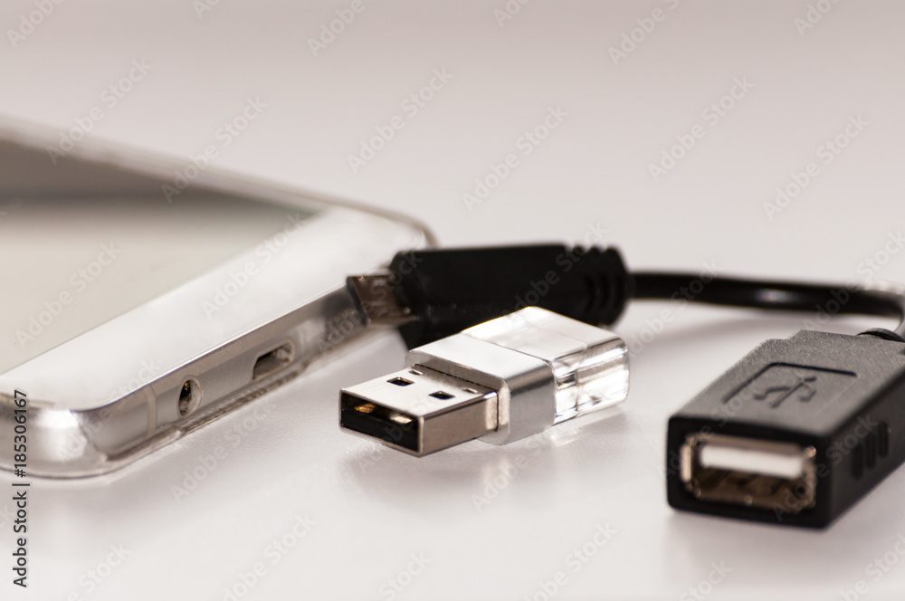 The smartphone next to which is usb flash memory and a cable for its connection to the smartphone. The smartphone next to which is usb flash memory and a cable for its connection to the smartphone.