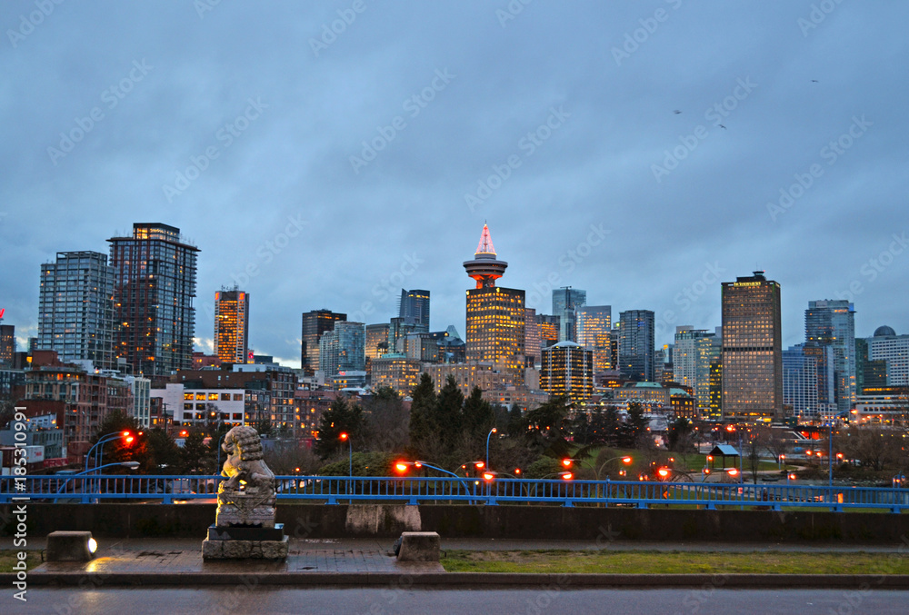 Fototapeta premium Vancouver, British Columbia, Canada, 2012. Skyline of the city from a wet street closed to the harbor at dusk lit by many artificial lights