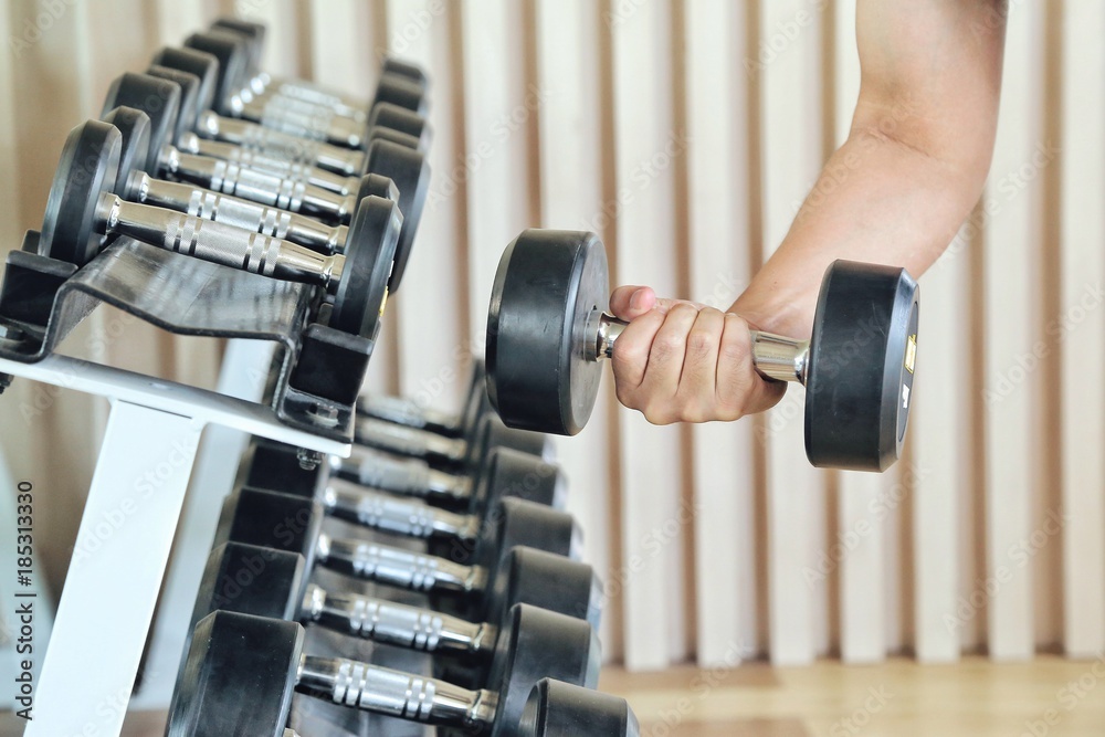 Close up of man holding weight in gym. fitness concept. holding dumbbell in fitness center. concept of healthy