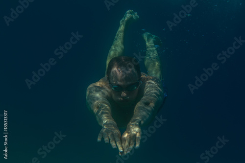 Tourist man in swimming sports glasses swimming underwater in the Aegean Sea on the coast of Sithonia Peninsula